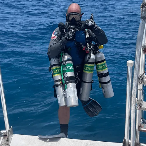 A technical diver rigged with stage cylinders for a deep dive on Roatán's wall